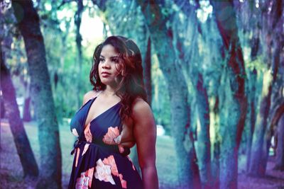 Woman looking away while standing in forest