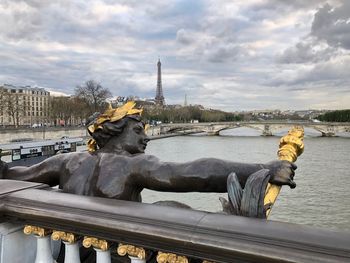 Statue by fountain in city against sky