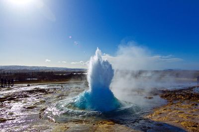 Water splashing on fountain against blue sky