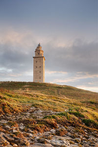 Lighthouse on field against sky