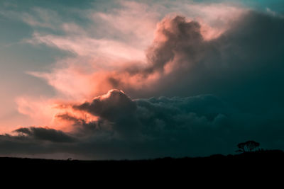 Low angle view of storm clouds over silhouette landscape