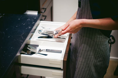 Midsection of woman holding eating utensils at kitchen