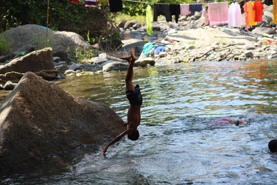 Side view of shirtless man on rocks at shore