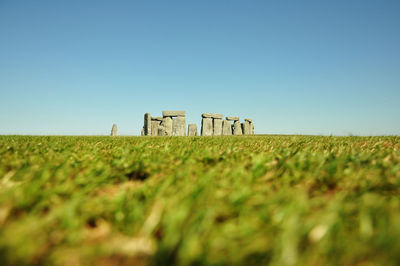 Stonehenge on grassy field against clear sky