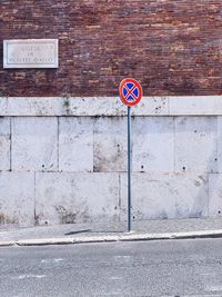 Information sign on road against wall