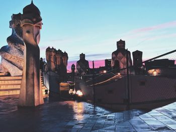 Statue amidst buildings in city against sky at sunset