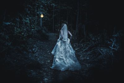 Rear view of bride running in forest