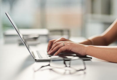 Cropped hands using laptop on table