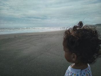 Girl at beach against sky