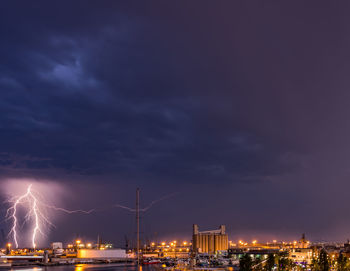 Panoramic view of illuminated city by a lightnin against sky at night during the storm. 