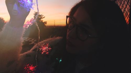 Close-up of child on tree at sunset