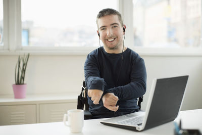 Portrait of happy disabled businessman with laptop at desk in office