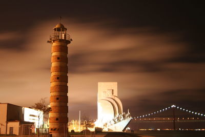 Illuminated lighthouse and padrao dos descobrimentos at night