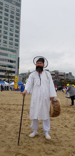 Portrait of man in traditional clothing standing on sand in city