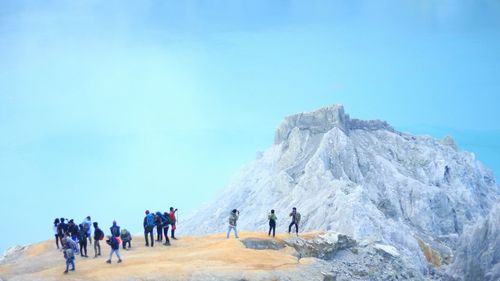 People on rock against blue sky