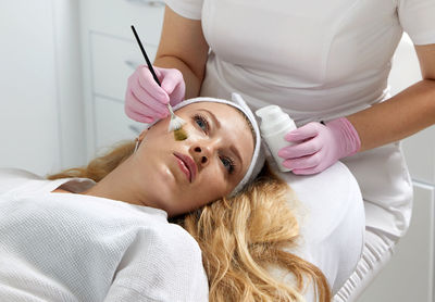 Midsection of woman applying make-up to daughter at home