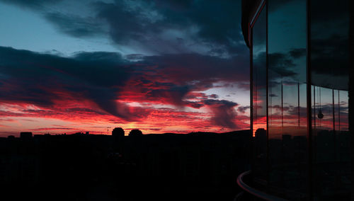 Silhouette buildings against dramatic sky during sunset