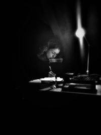 Woman sitting at table in darkroom