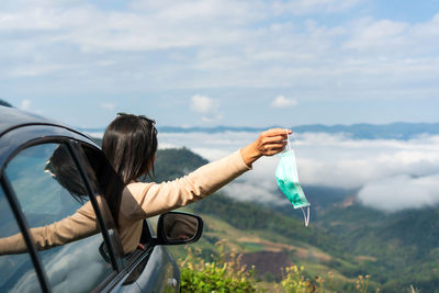 Rear view of woman holding umbrella against sky