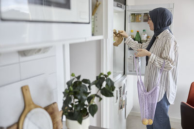 Woman in headscarf unpacking groceries at home