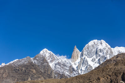 Low angle view of snowcapped mountains against clear blue sky