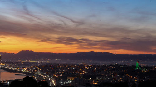 High angle view of illuminated cityscape against sky during sunset