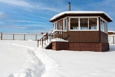 House on snow covered field against sky