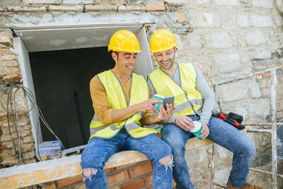 Two construction workers looking at a cell phone at break time