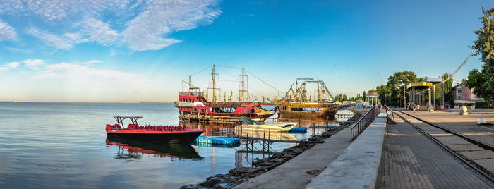 Fishing boats moored at harbor against sky