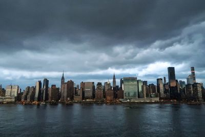 Sea by city against cloudy sky