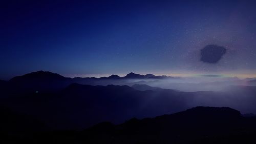 Silhouette mountains against clear blue sky at night