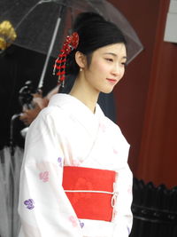 Young woman in kimono looking away while standing outdoors