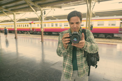 Man holding camera standing at railway station