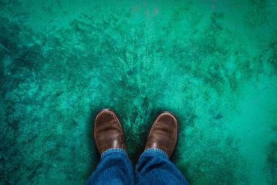 Low section of man standing against blue wall