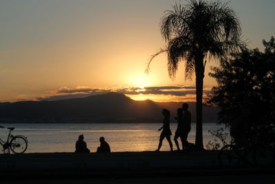 Silhouette people against lake during sunset