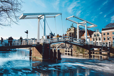 Bridge over river by city against sky