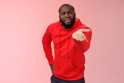 Portrait of young man standing against red background