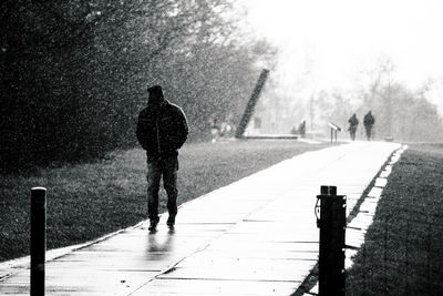 Man walking on footpath in rain