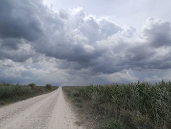 Road amidst field against sky