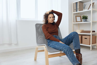 Worried woman sitting on chair at home