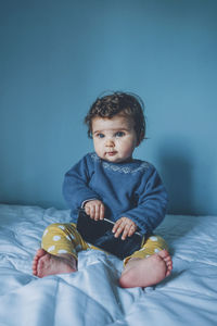 Cute girl sitting on bed at home