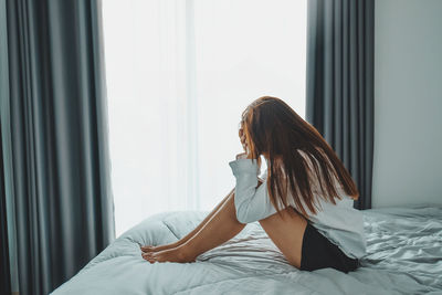 Woman sitting on bed at home