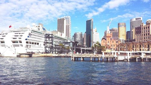 City at waterfront against cloudy sky