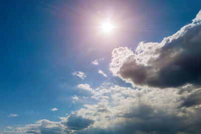 Low angle view of sunlight streaming through clouds