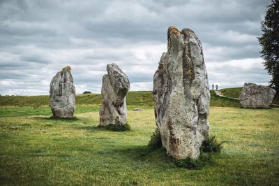 Rocks on field against cloudy sky