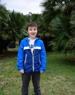 Portrait of smiling boy standing against trees in park