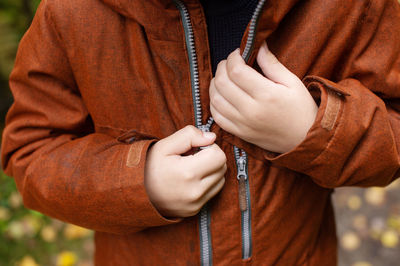 Children's hands zip up the red jacket