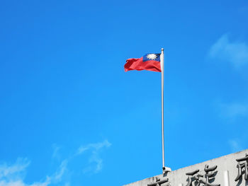 Low angle view of flag against blue sky