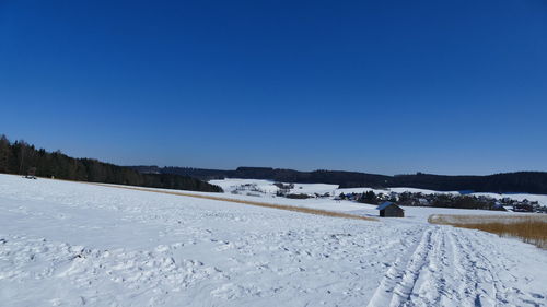 Scenic view of snow covered landscape against clear blue sky