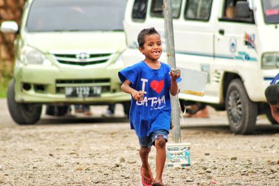 Portrait of happy boy standing on car